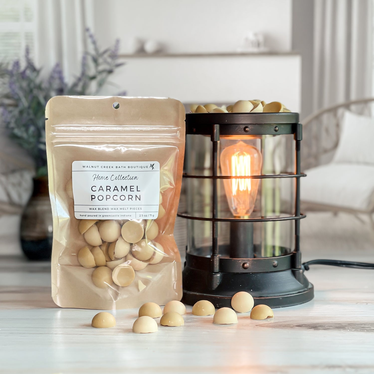 caramel popcorn wax melt bag next to lit burner. there are wax melts on the table scattered about to shoe the pieces - these are light tan and light brown dot pieces