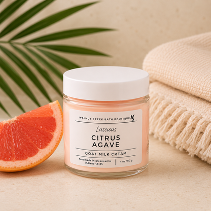 Jar of Citrus Agave goat milk cream with a slice of grapefruit and towel on a neutral background