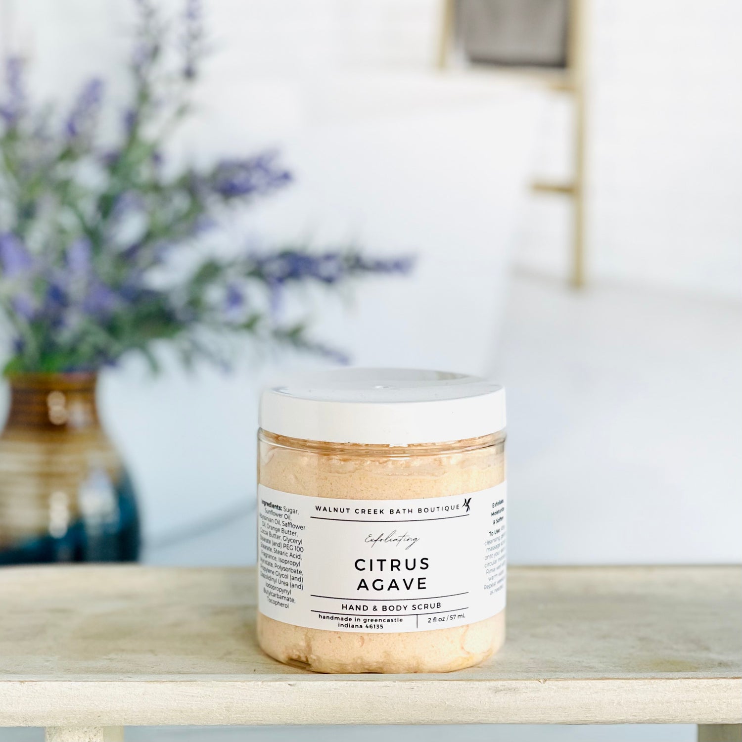 citrus agave scrub is shown on a tray. there is some lavender in the background to give interest to this very calm and neutral image to evoke a peaceful experience. 