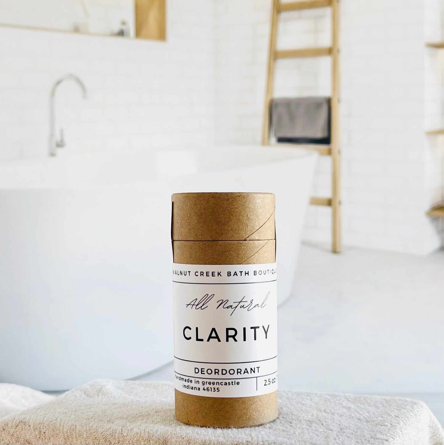 claridy deodorant is shown, the label is minimalist in design, white with black lettering. in the background is a spa like bathroom