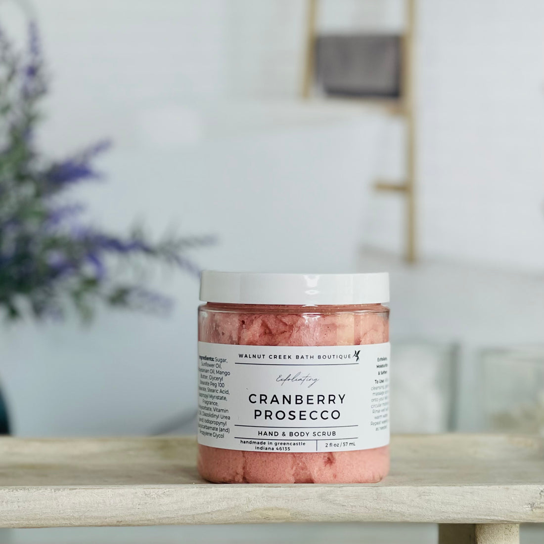 cranberry prosecco scrub is shown on a tray. there is some lavender in the background to give interest to this very calm and neutral image to evoke a peaceful experience. 