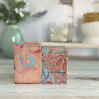 Two marbled patterned soaps on a wooden surface with a blurred background