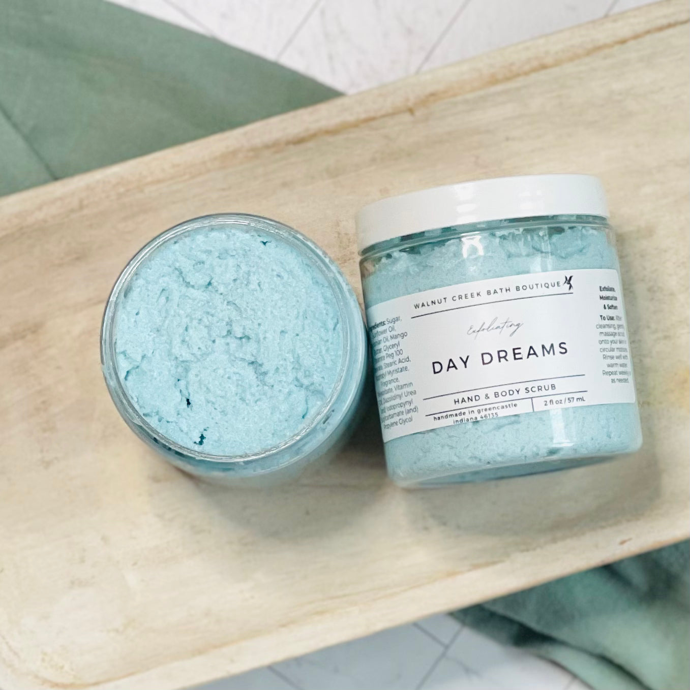 Day dreams scrubs with one laying flat and the other next to it with the top off to show the blue scrub inside of the jar