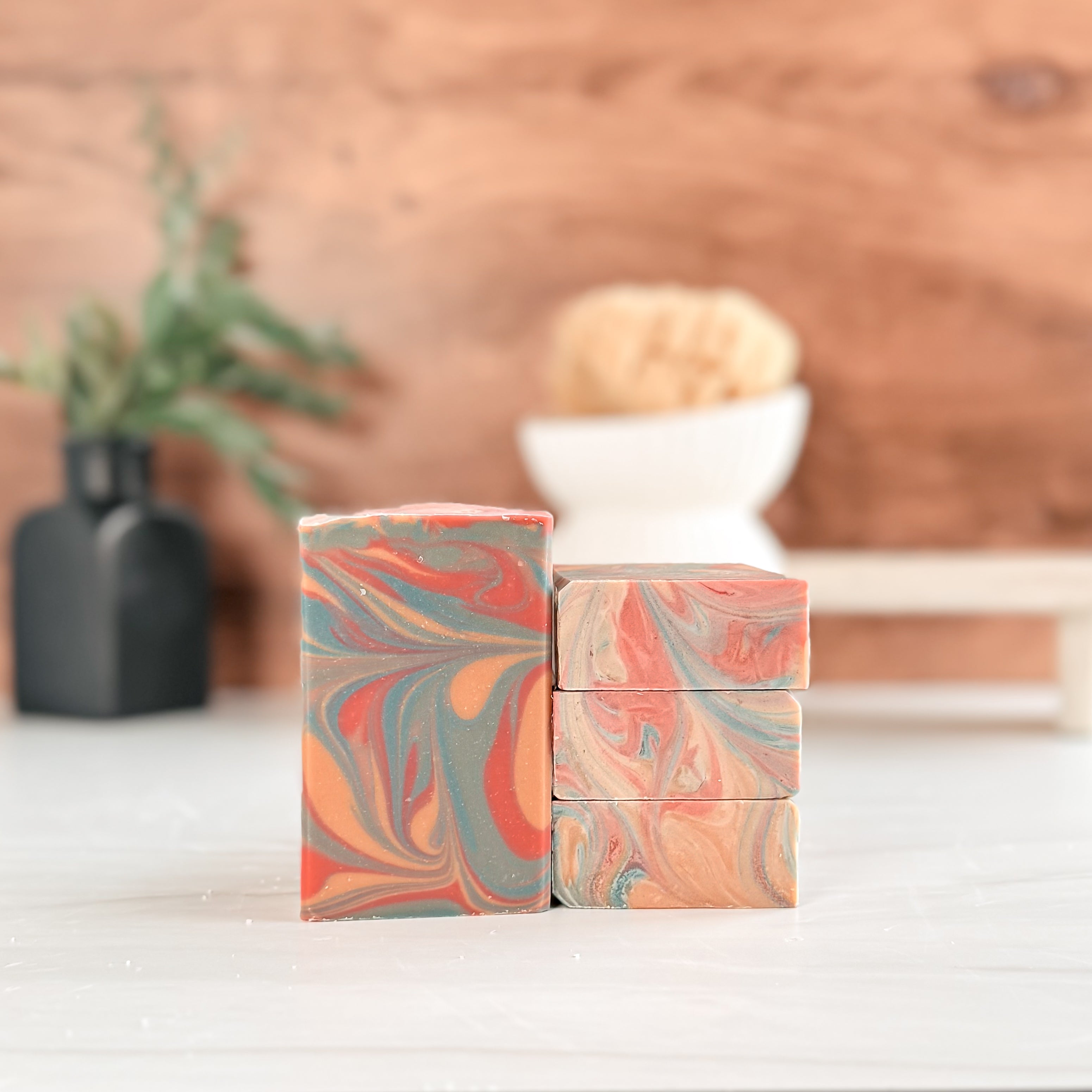 Marbled soap bars stacked on a wooden surface with a blurred background