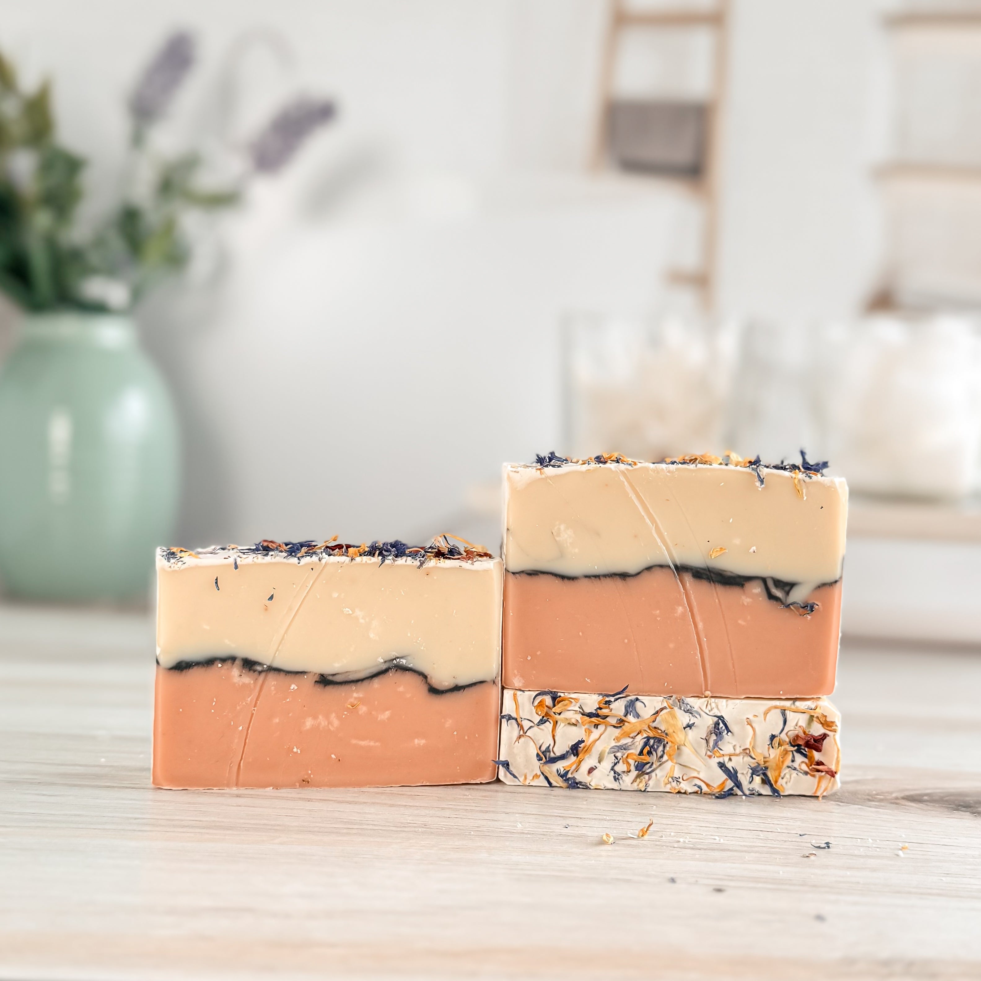Two layered soap bars on a wooden surface with a blurred background
