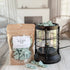 Packaged Fraser Fir wax melts next to a lantern with wax melts on a wooden surface.