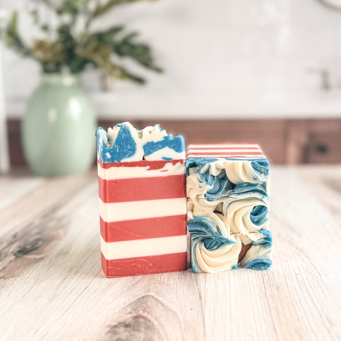 Two soap bars with red, white, and blue patterns on a wooden surface.