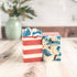 Two soap bars with red, white, and blue patterns on a wooden surface.