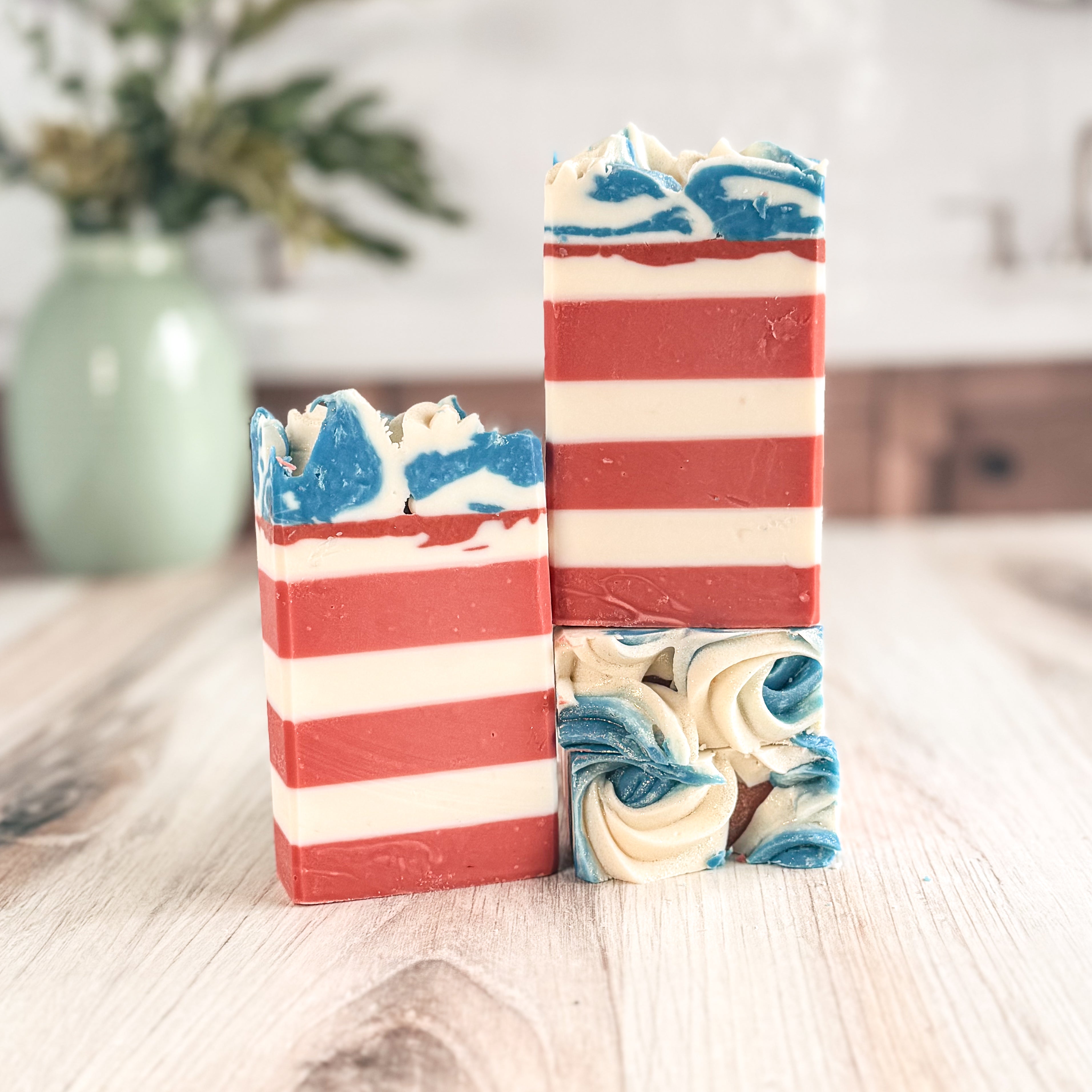 Two bars of soap with red, white, and blue stripes on a wooden surface.