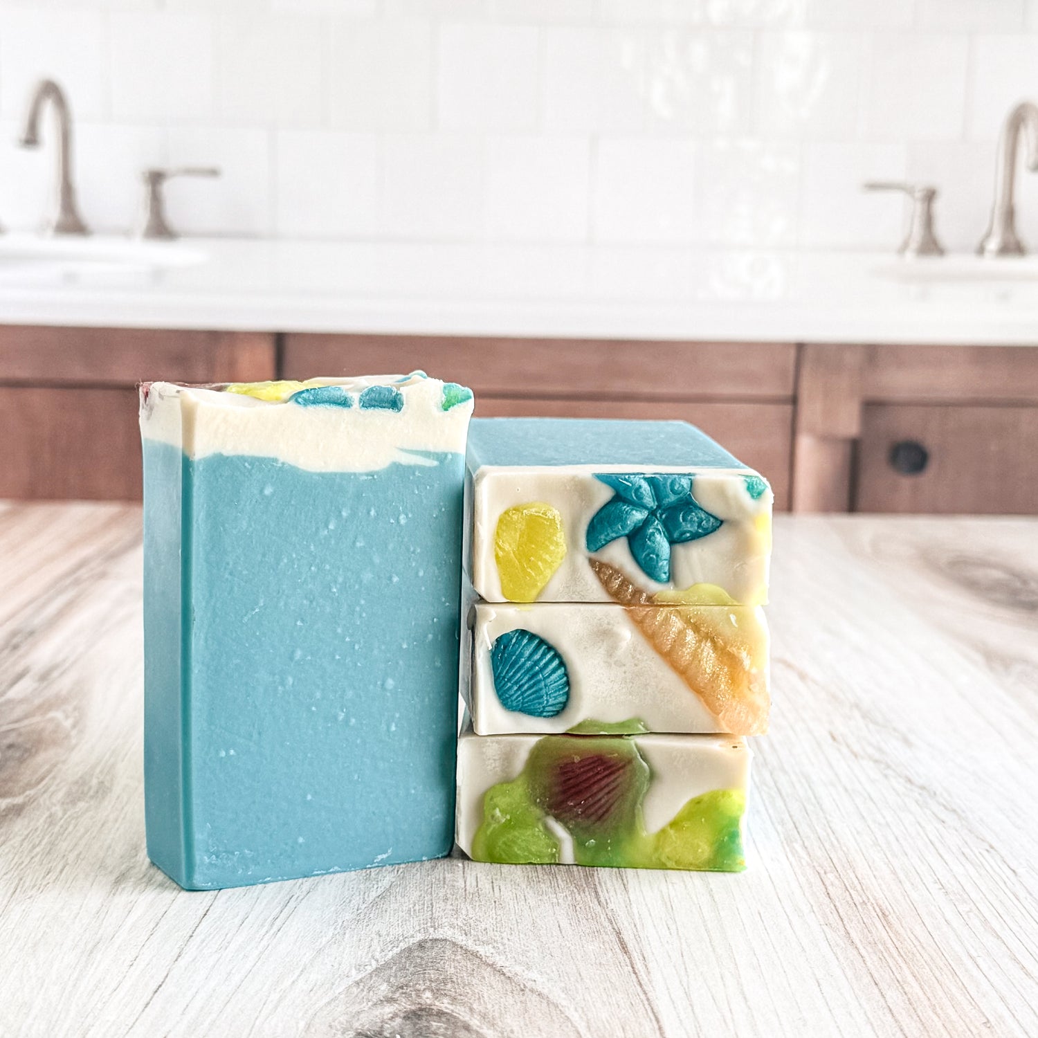 Stack of colorful soap bars on a wooden surface with a kitchen background