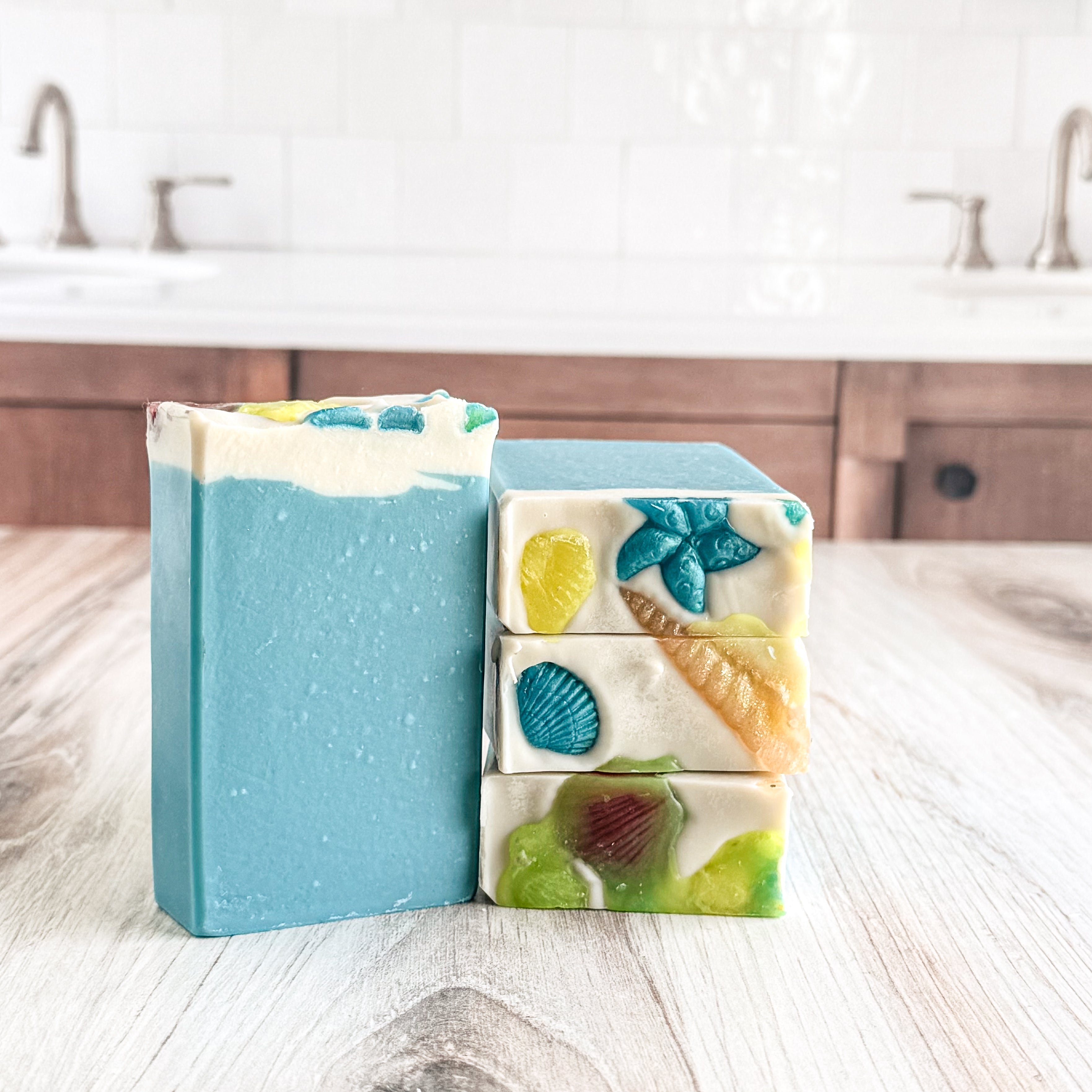 Stack of colorful soap bars on a wooden surface with a kitchen background