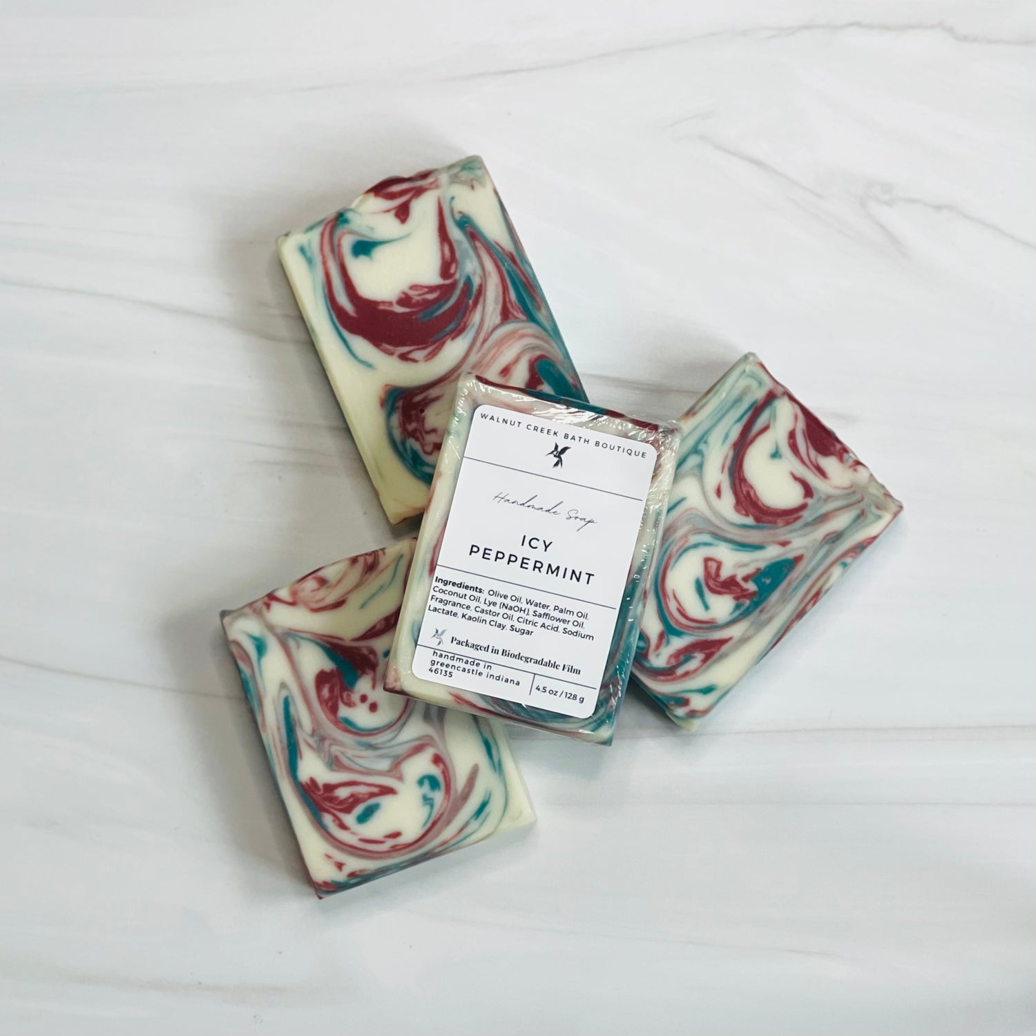 3 icy peppermint soaps are shown in a circular fan shape showing the  red and green swirls, there is a 4th soap laying across all the soaps to show the label.