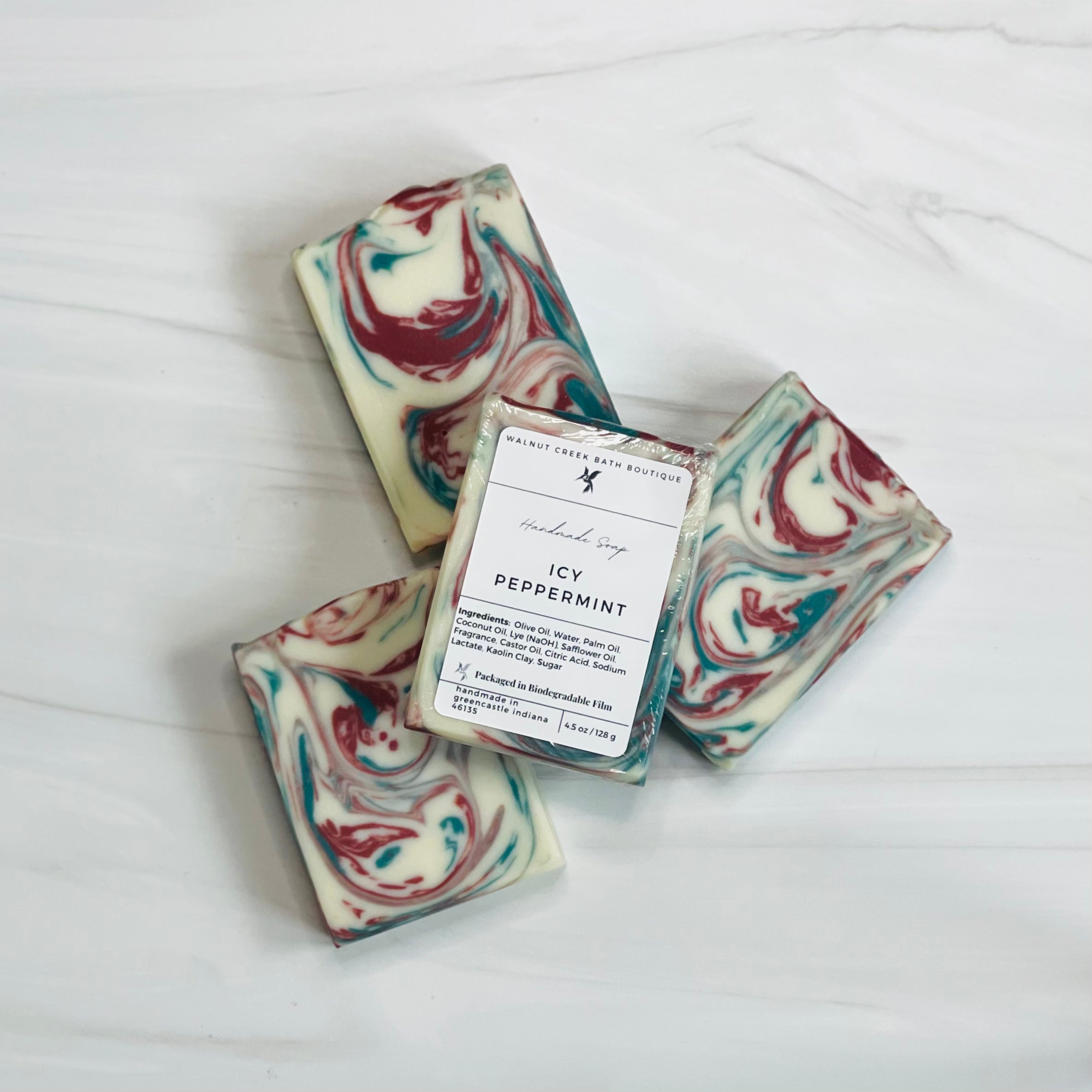 3 icy peppermint soaps are shown in a circular fan shape showing the  red and green swirls, there is a 4th soap laying across all the soaps to show the label.