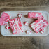icy peppermint soaps are sitting on a light colored wood tray. 2 are laying flat showing red and pink swirls, two are standing tall showing the pretty swirled tops. there are also some hard peppermint candy scattered around the soaps