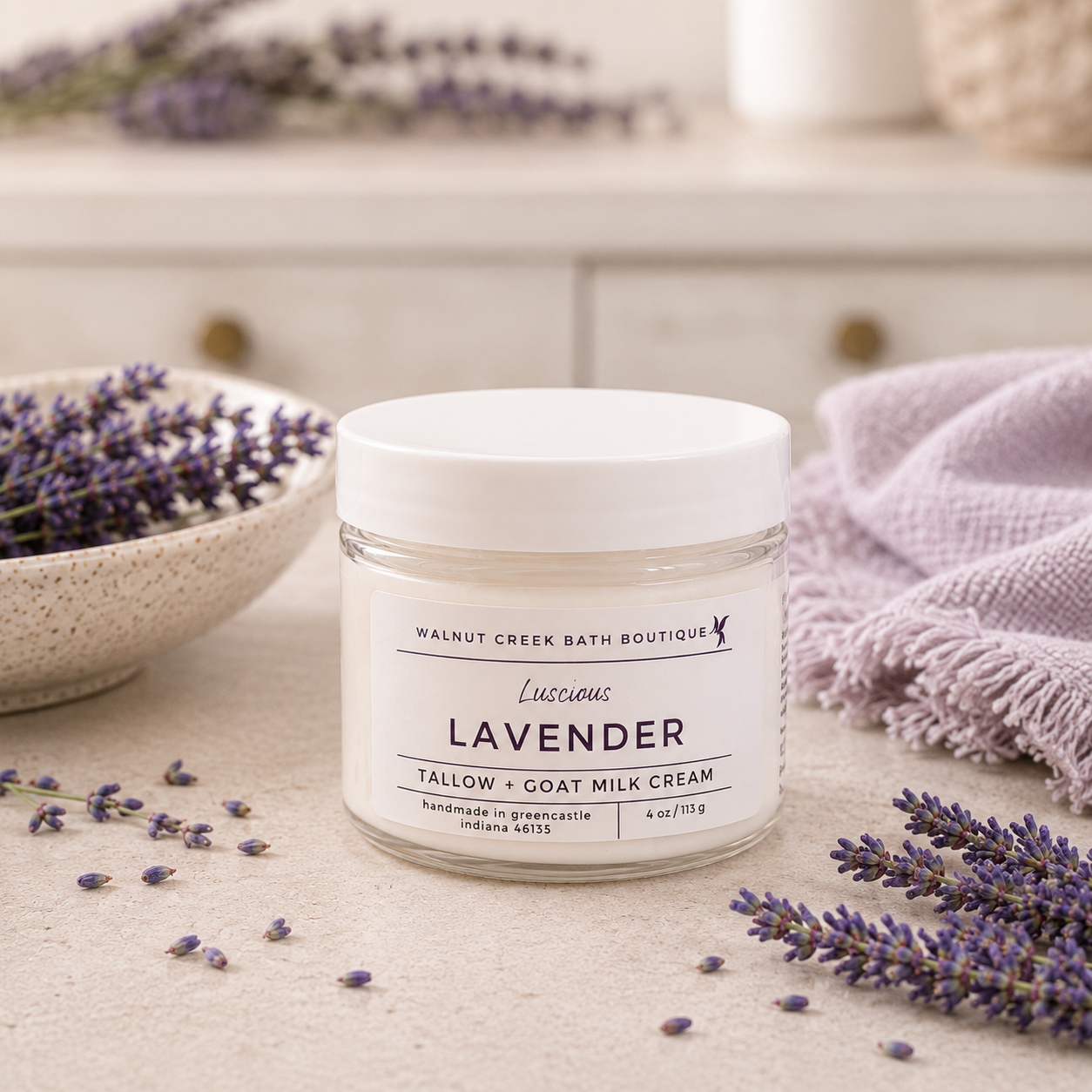 Jar of lavender cream from Walnut Creek Bath Boutique on a surface with lavender flowers.