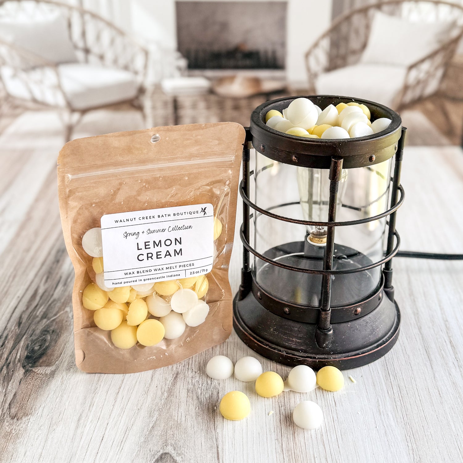 Packaged lemon cream wax melts next to a lantern on a wooden surface.