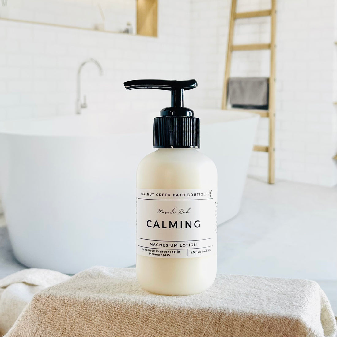 magnesium lotion is in an opaque bottle with a black pump. it is sitting in front of a very pretty bathtub.