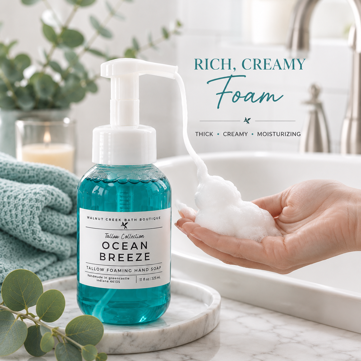 A bottle of Ocean Breeze Thick Creamy Foam hand soap sits on a marble tray beside a sink, with a hand dispensing white foam into the palm. Text on the image reads &