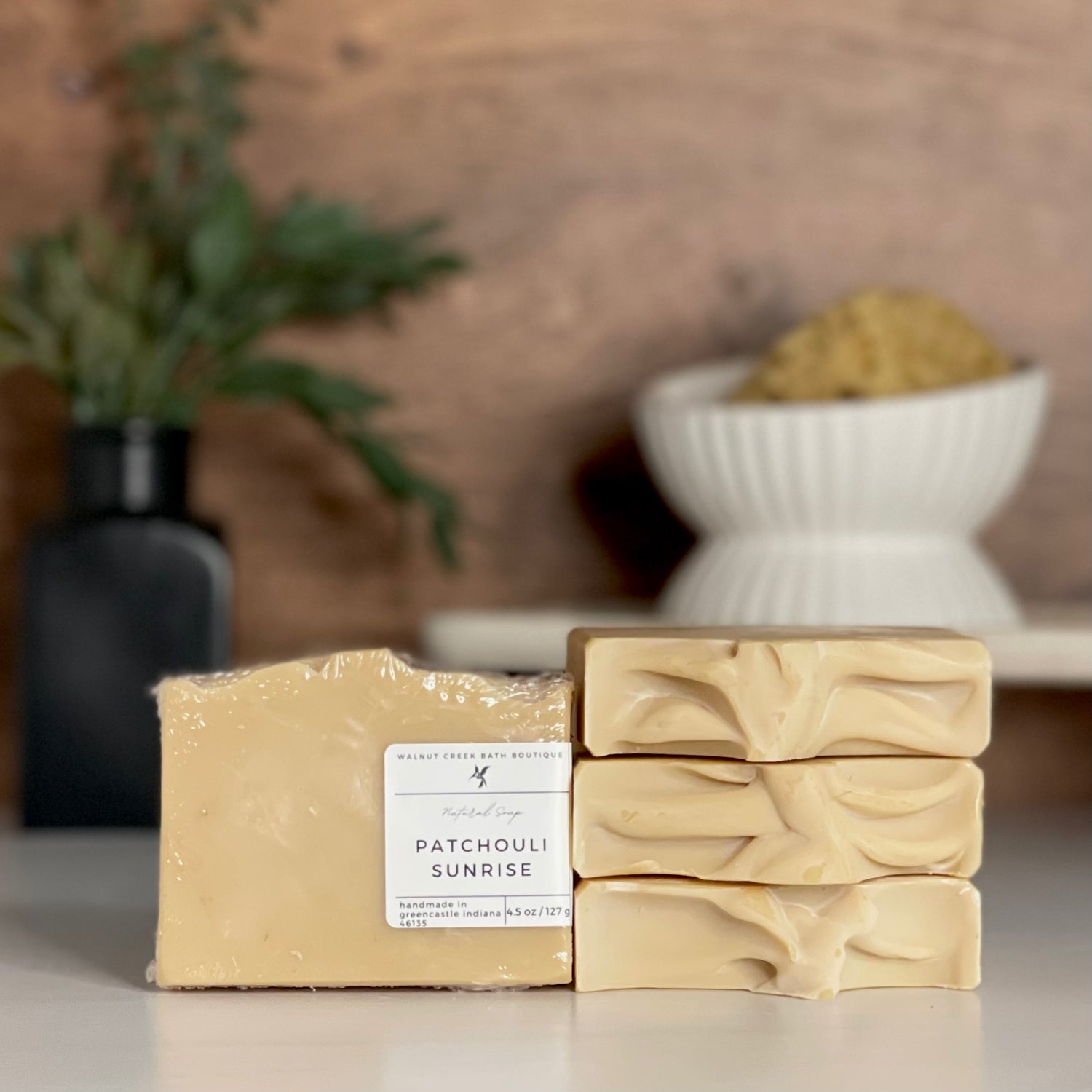 a patchouli sunrise soap is standing tall packaged in it&