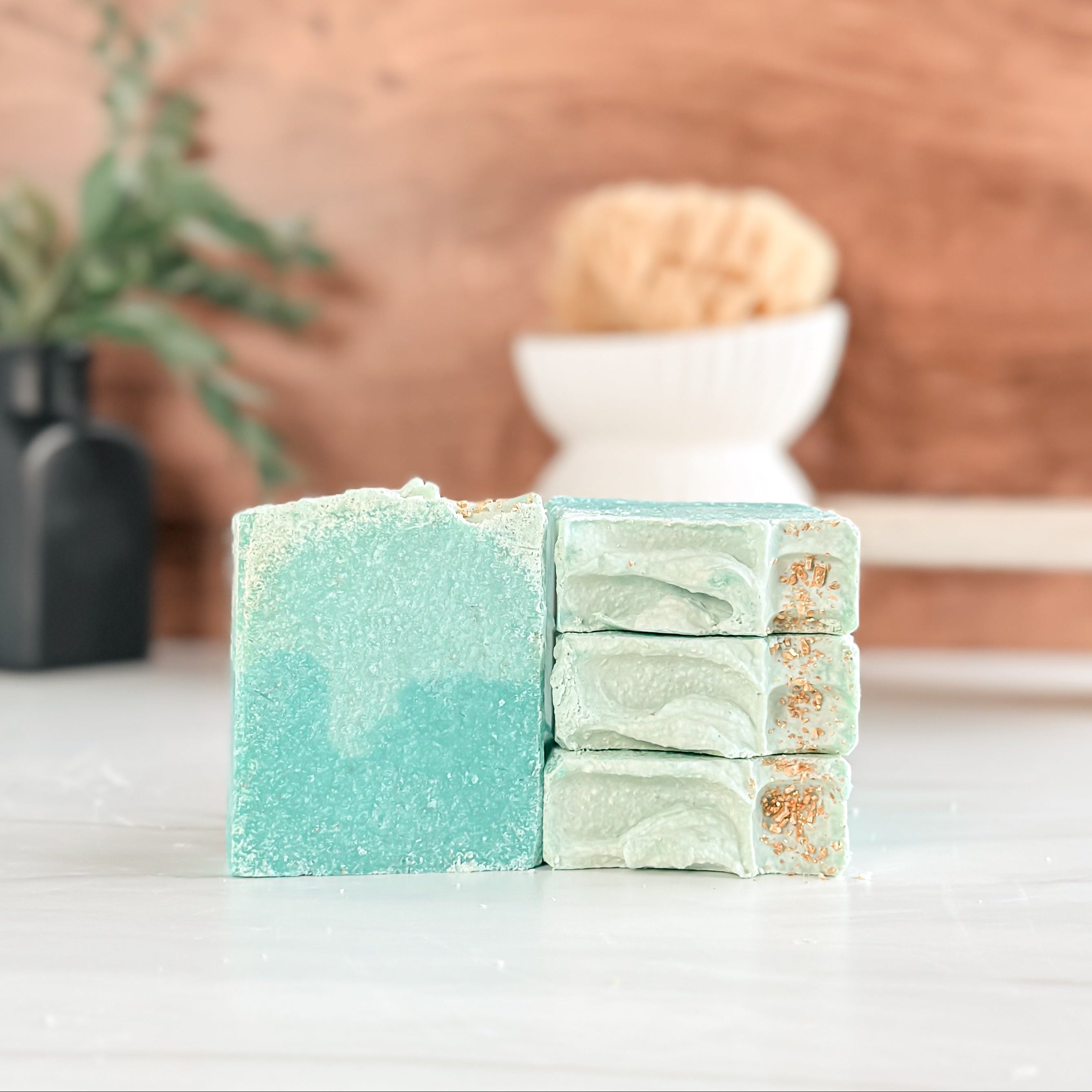 Stack of green and blue soap bars on a white surface with a wooden background