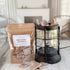 Packaged Snickerdoodle wax melts next to a decorative lantern on a wooden surface.