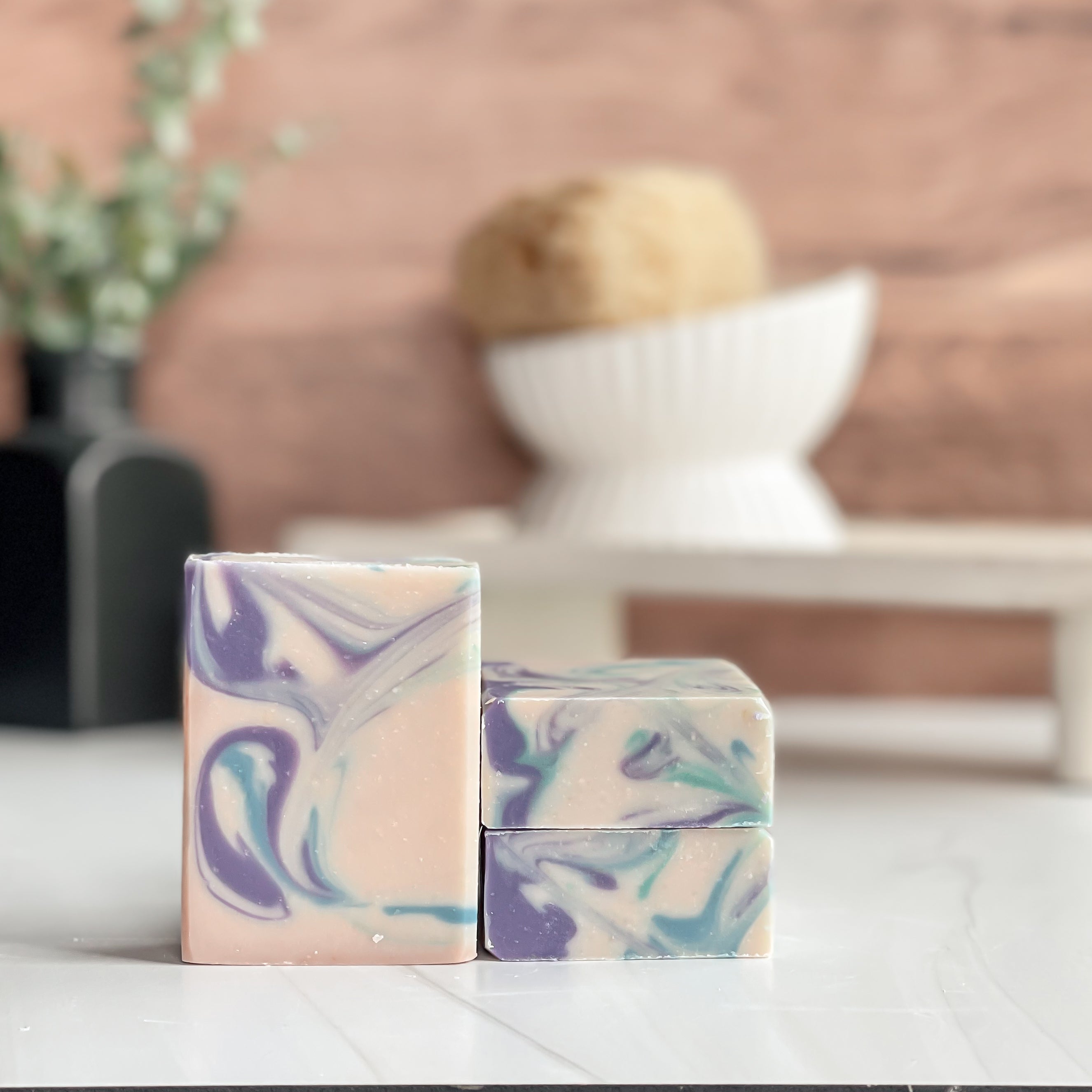 Two marbled soap bars on a white surface with a blurred background