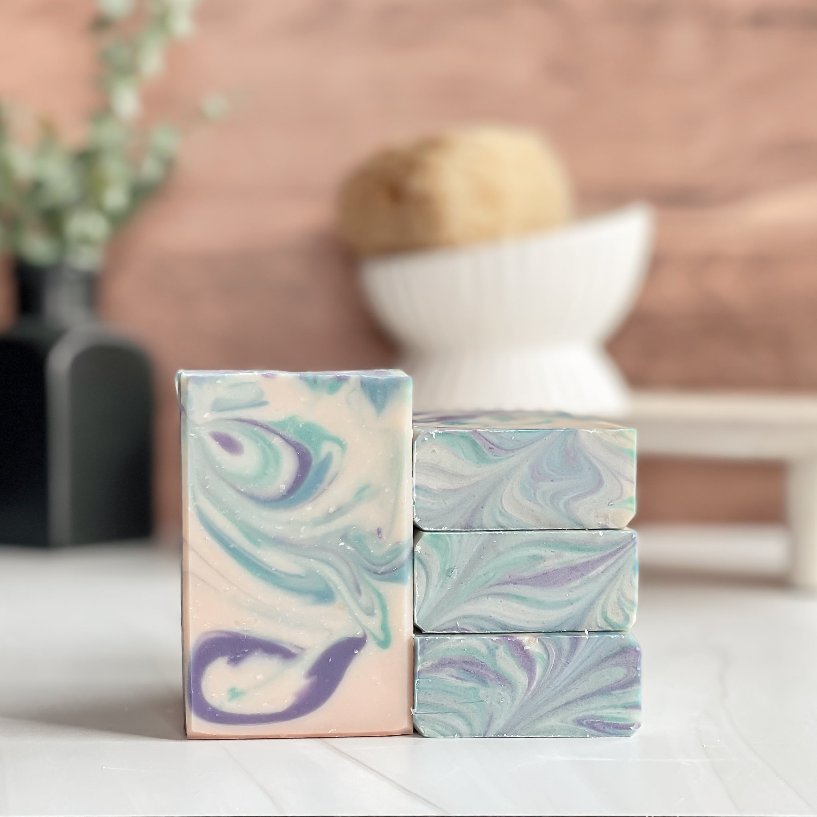 Stack of marbled soap bars on a white surface with a blurred background