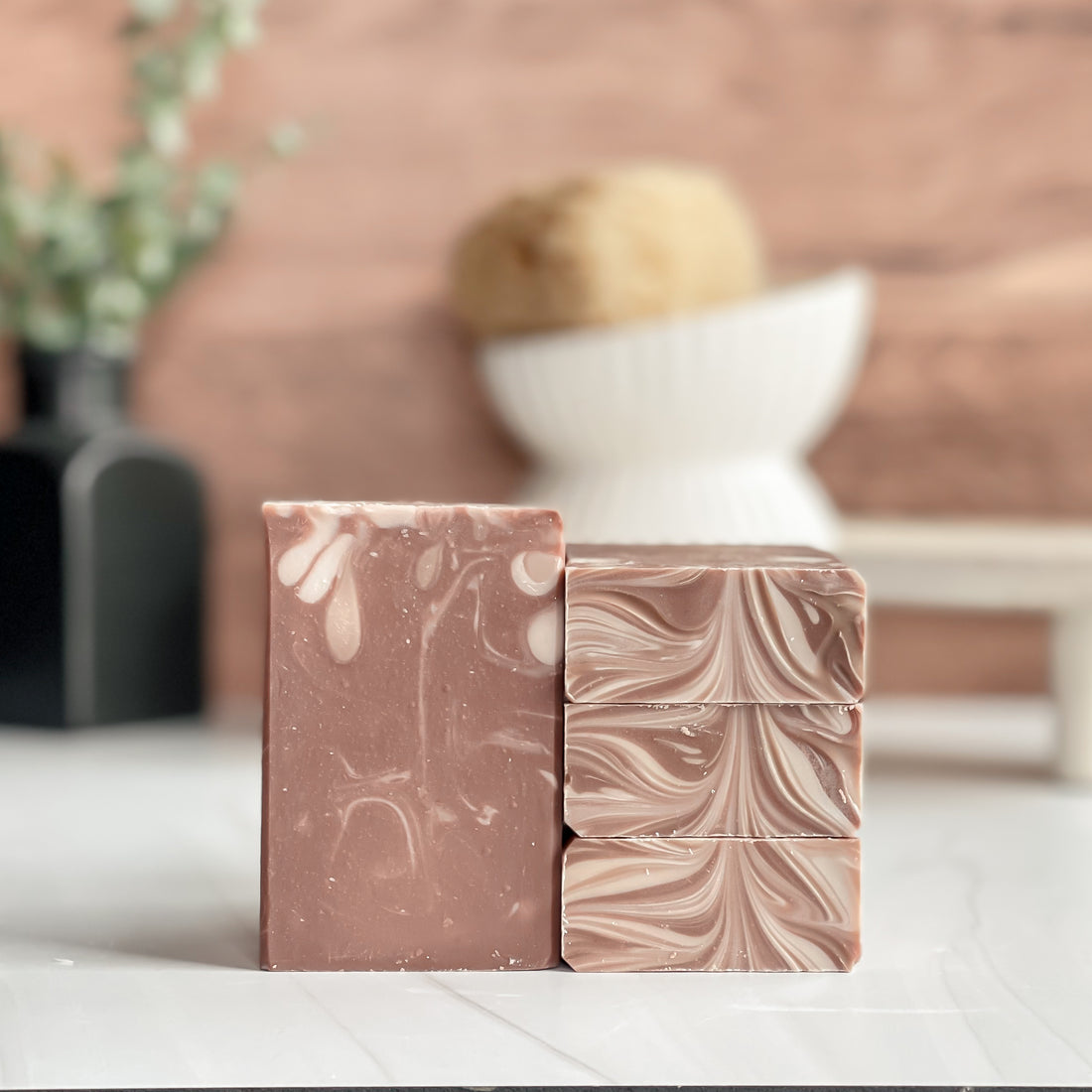 Two marbled soap bars on a white surface with a blurred background