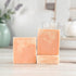 Three bars of soap stacked on a wooden surface with a blurred background