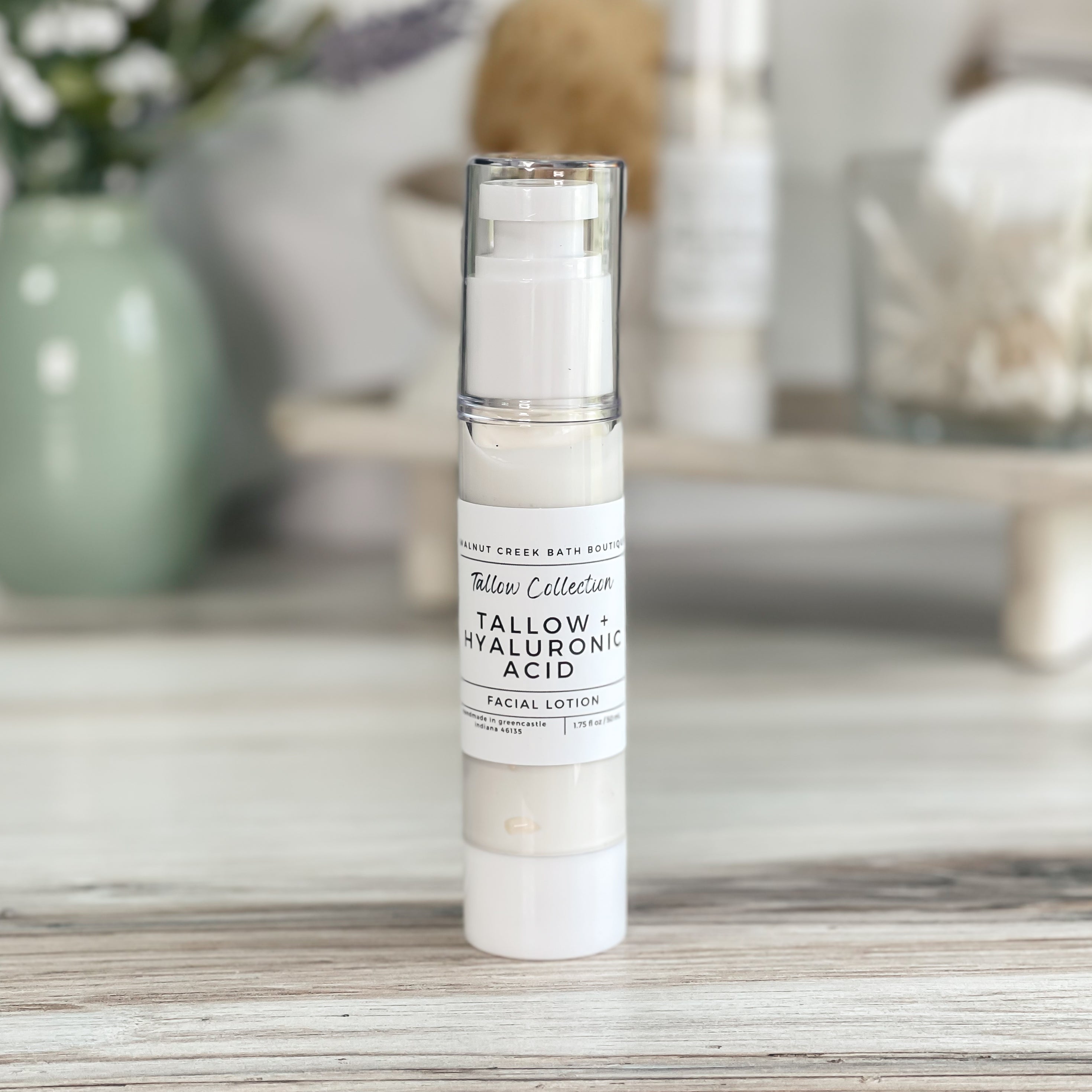 tallow and hyaluronic acid face lotion in airless bottle sitting on pale wood surface