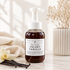 A bottle of Walnut Creek Bath Boutique Velvet Vanilla Fallow Foaming Hand Soap stands on a marble surface with a beige towel, vanilla beans, and dried flowers in the background.
