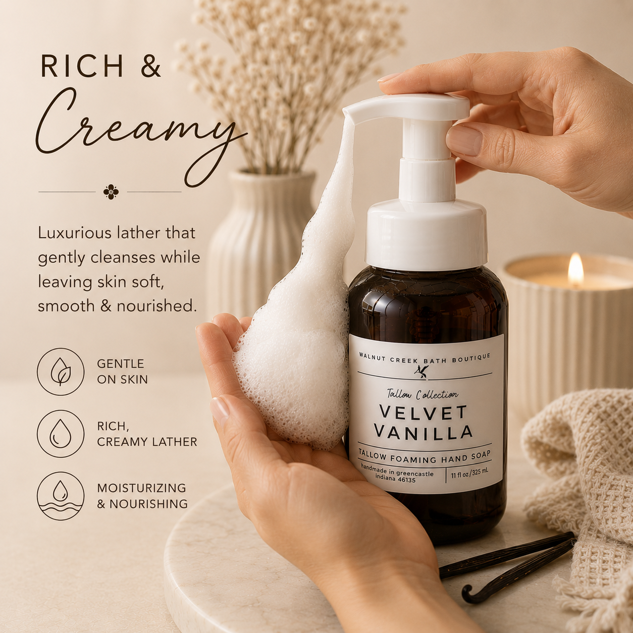 A person holds a white foam dispenser over a dark amber bottle of Walnut Creek Bath Boutique Velvet Vanilla yellow foaming hand soap, with a soft lather being transferred onto a hand. The scene is styled with a lit candle, dried flowers, and a knit blanket on a marble surface, with text on the left describing the rich creamy lather.