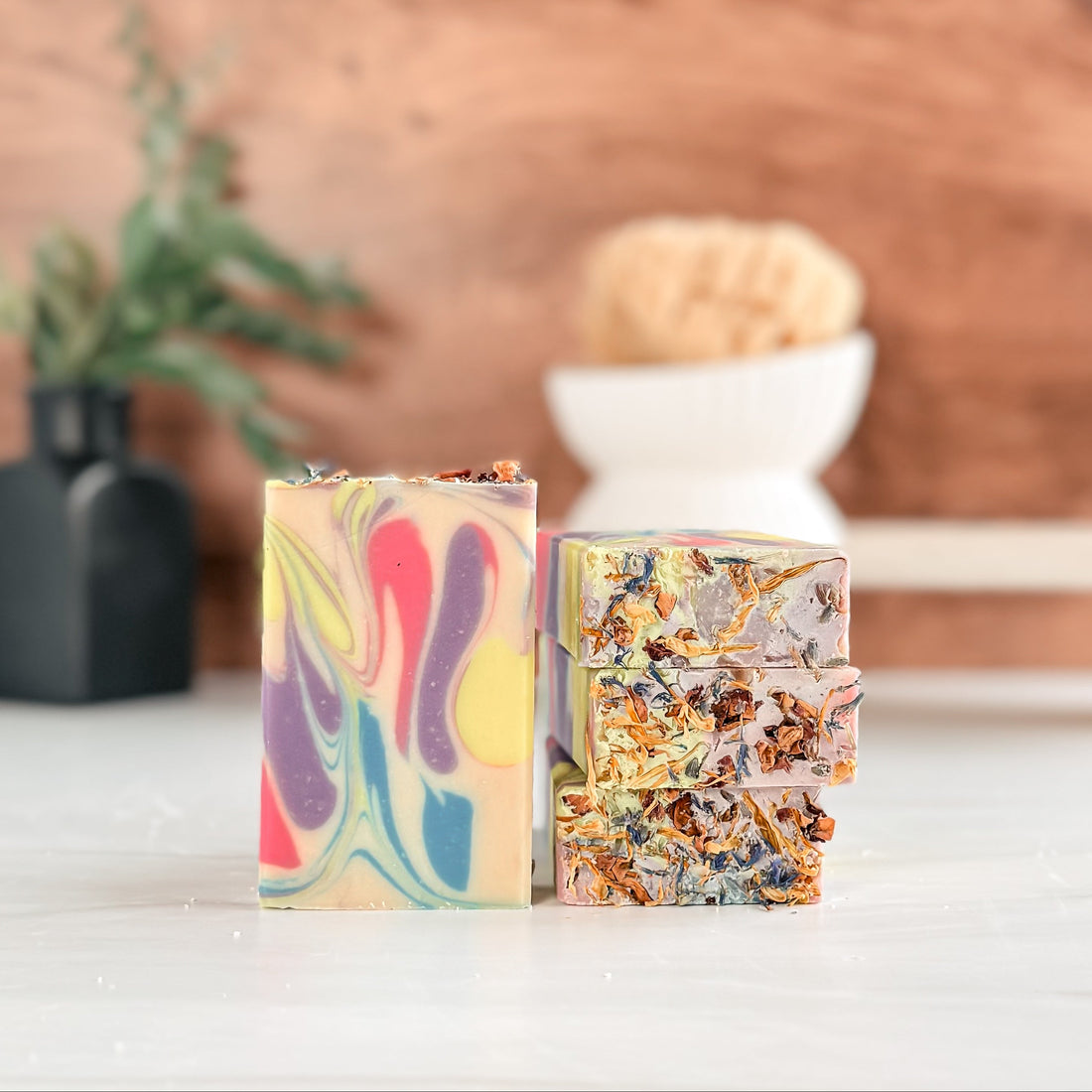 Two colorful soap bars on a wooden surface with a blurred background