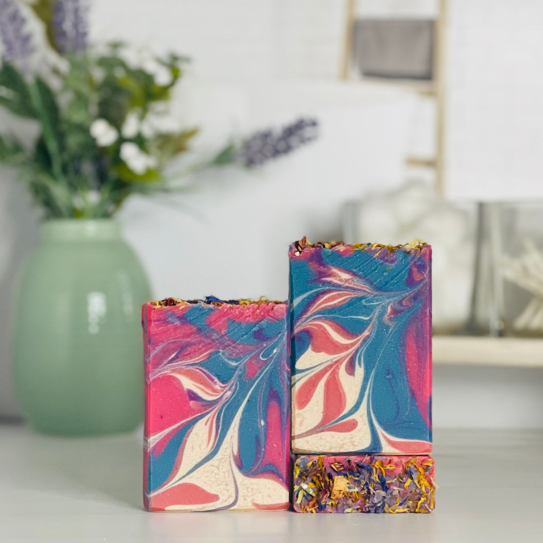 one wildflower breeze soap is standing next to one laying flat to show the top and another standing on the flat one to show more of the soap colors