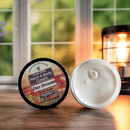 4 oz day dreams cream, one with top showing a pretty label of pink flowers, next to this is an open jar showing contents. There is a lush green background behind a window and a light in the back right.