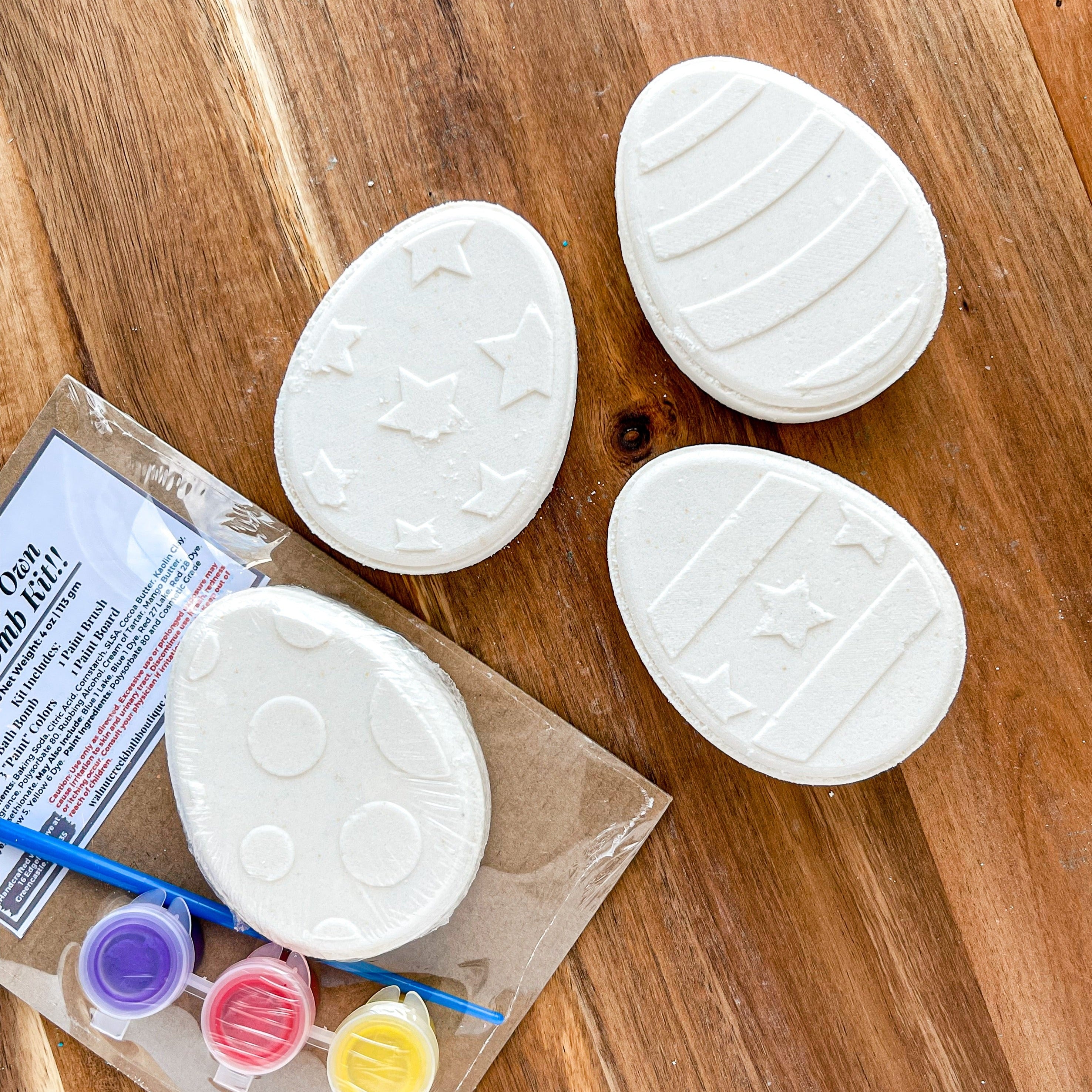 4 white easter egg bath bombs next to the kit with the paint brush and paint